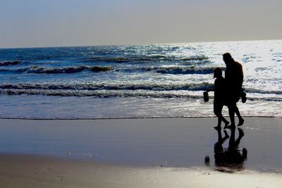 Silhouette man standing on beach against clear sky