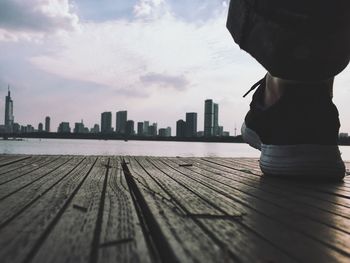 Low section of woman in city against sky