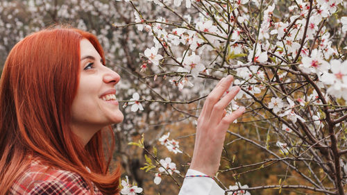 Happy red-haired girl under spring flower tree. spring mood.