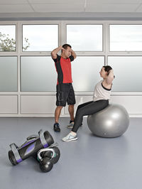Personal trainer helping client at gym in the uk