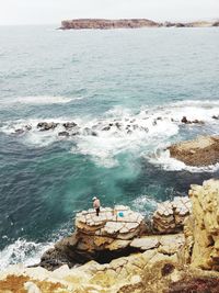 Aerial view of man fishing by sea while standing on rock