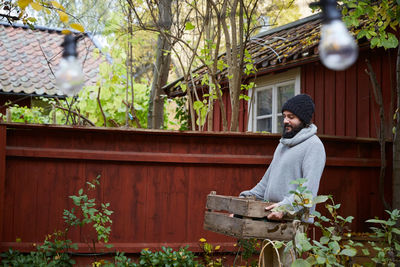 Smiling man walking with vegetable basket in yard