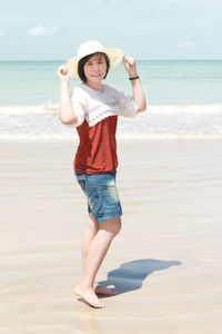 Portrait of young woman wearing hat while standing at beach