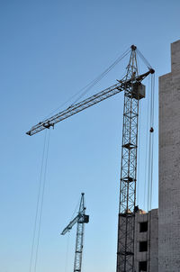 Low angle view of crane against clear blue sky