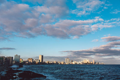 Sea by buildings in city against sky