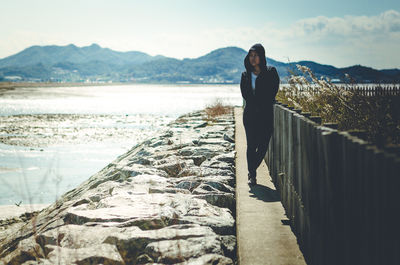 Woman standing on cliff by sea