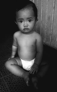 Portrait of baby boy sitting on floor at home