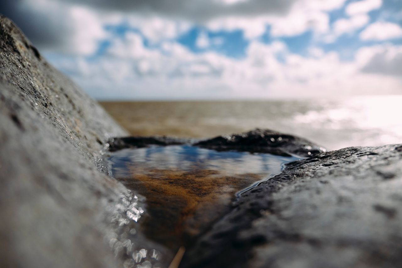 horizon over water, sea, selective focus, water, beach, tranquil scene, scenics, sky, rock - object, tranquility, beauty in nature, shore, nature, cloud - sky, surface level, outdoors, day, non-urban scene, seascape, no people, wave