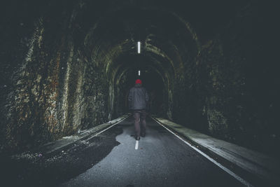 Rear view of man walking in tunnel