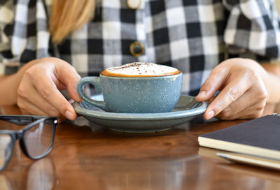 Midsection of woman using mobile phone on table