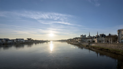 Scenic view of river by buildings against sky