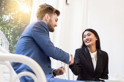 Low angle view of business people doing handshake while sitting in office