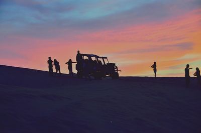 Silhouette people by buggy at desert during sunset