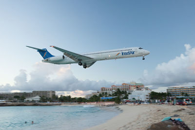 Airplane flying over water against sky