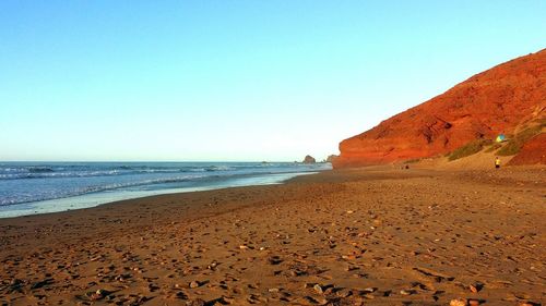 Scenic view of beach against clear blue sky