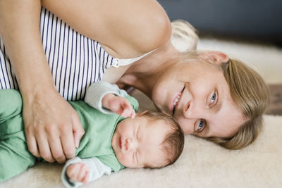 Portrait of mother relaxing with baby on bed