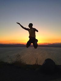 Full length of silhouette man jumping at sunset