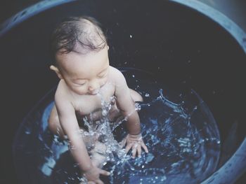Full length of cute baby boy splashing water in bathtub