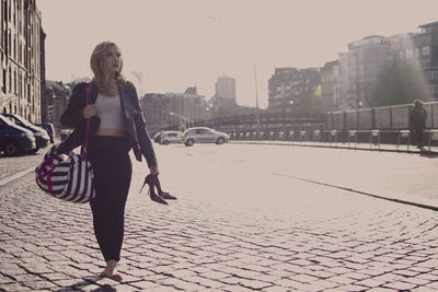 Full length of woman walking on street in city against sky