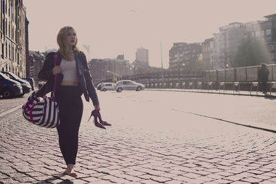 Full length portrait of young woman walking on street in city