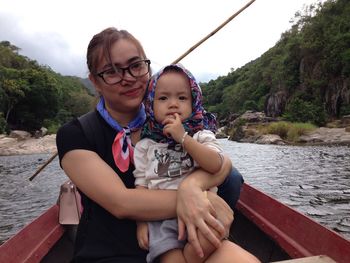 Portrait of mother with son traveling in rowboat on river