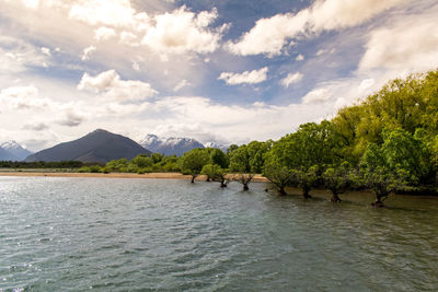 Scenic view of river by mountains against sky