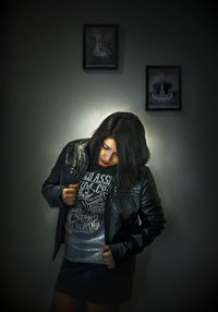 Portrait of young woman standing against wall at home