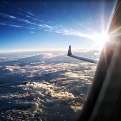 Airplane flying over cloudscape against sky at sunset