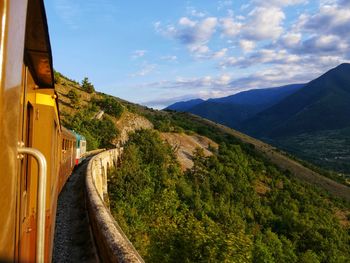 Train passing through mountains against sky