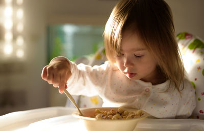 Close-up of cute girl eating food at home