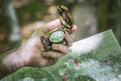Hiker locating a path in the forest with a compass and a map
