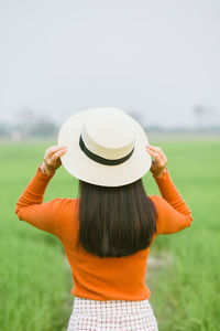 Rear view of woman wearing hat standing on field