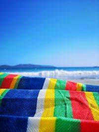 Close-up of multi colored umbrellas on beach against clear blue sky