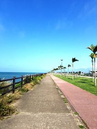 Road by sea against blue sky