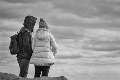 Rear view of couple standing against cloudy sky