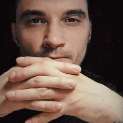 Close-up portrait of young man over black background