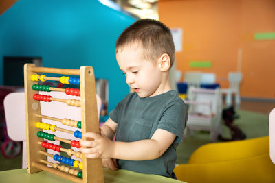 Toddler boy playing with colourful toy abacus in a children's entertainment center.