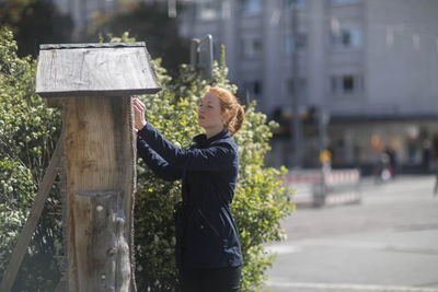 Young woman in a urbanic garden in a city near a bee house