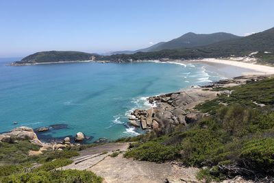 Scenic view of sea and mountains against clear blue sky