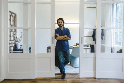 Portrait of man standing against door at home