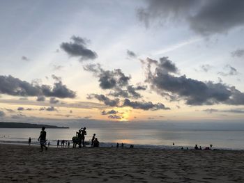 Silhouette people on beach against sky during sunset