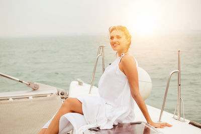 Young woman sitting on boat against sea against sky