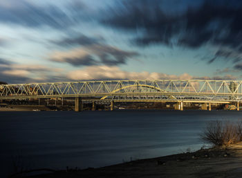 Bridge over river against cloudy sky