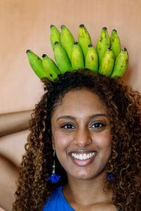 Beautiful african woman with long curly hair smiling holding bunch of bananas as a crown