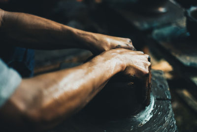 Cropped hands of man making pot at workshop