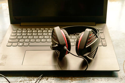  headphone placed near laptop on window sunlight in morning. red cup of coffee at a distance. 