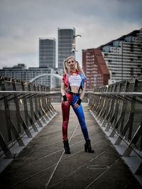 Portrait of young woman standing against railing in city