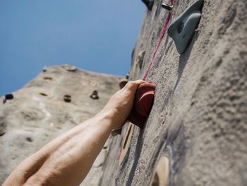 Cropped image of man climbing on wall against clear sky