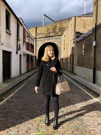 Smiling woman standing on street against building in city