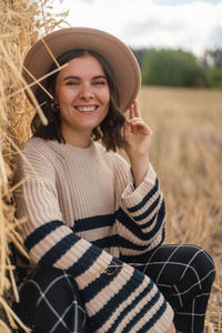 Portrait of smiling young woman wearing hat on field